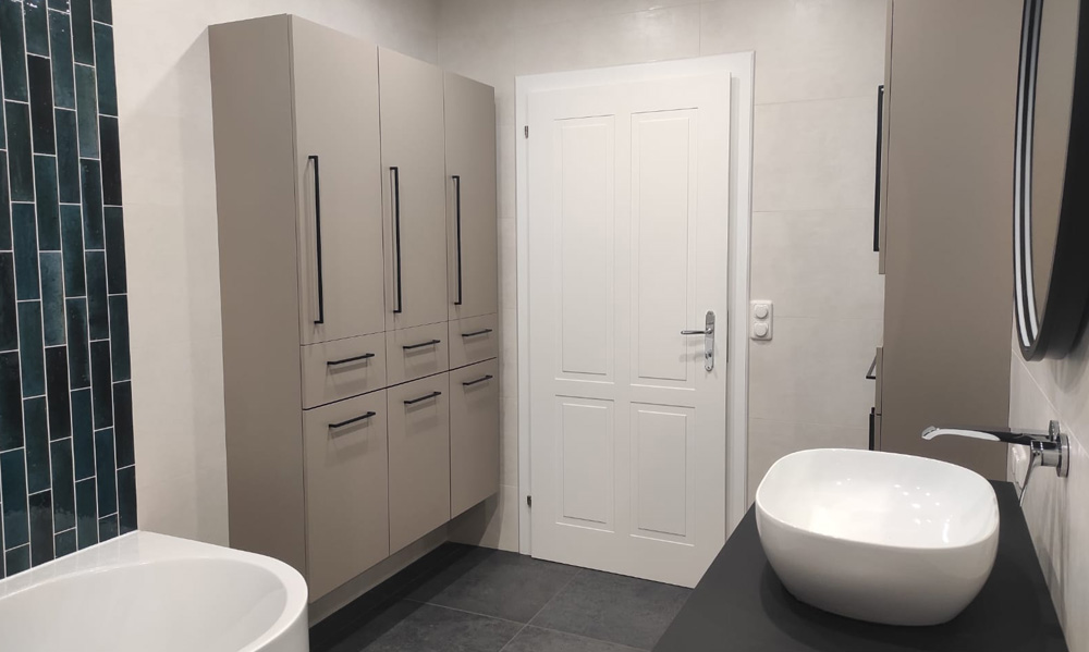 Modernes Badezimmer mit grauen Fliesen, Einbaumöbeln in Beige, weißer Tür und Waschtisch mit Aufsatzwaschbecken